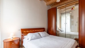 A bedroom with a wooden headboard, a bedside table with a lamp, and a large mirror on the wall. - A 100 Metri da Piazza Duomo di Ortigia by Wonderful Italy (Syracuse)