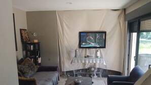 Uma sala de estar com sofá, mesa de centro e televisão na parede.