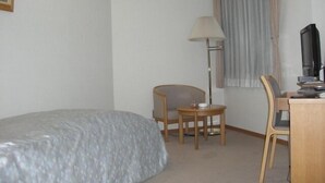 A hotel room with a bed, a desk with a chair, a lamp, and a television. - Espoir Iwate (Morioka)