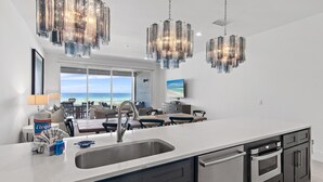 A modern kitchen with a large island, stainless steel appliances, and a view to the outdoors. - Henderson Beach Villa #2 (Destin)