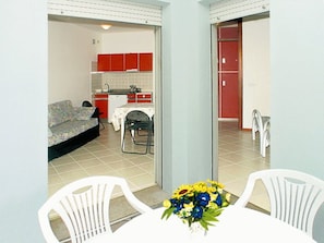 Um espaço de estar compacto com cozinha compacta, sofá, mesa de jantar com cadeiras e um banheiro pequeno.