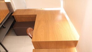 Un bureau en bois moderne, accompagné d’une chaise, d’un meuble et d’un petit tabouret.