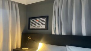 Une chambre d’hôtel avec un lit, une table de chevet avec une lampe et un tableau encadré au mur.