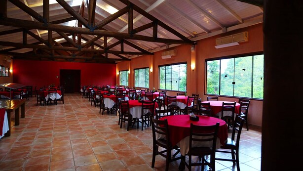 Ein Restaurant mit roten Tischen und Stühlen, großen Fenstern und einem gefliesten Boden.