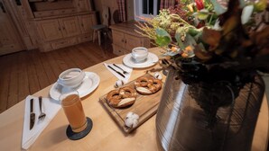 A wooden dining table with plates, cutlery, a glass of beverage, pretzels, and a vase with flowers. - LIBORIA Alpenblick country house (Uffing am Staffelsee)