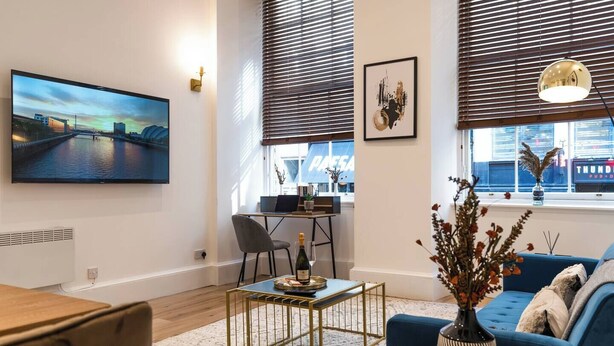 Una sala de estar moderna con un televisor grande, una zona de comedor y un sofá.