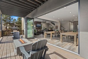 A modern outdoor patio with a fire pit, seating, and a view of the interior.