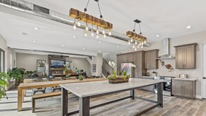 Een ruime keuken met houten kastjes, een groot eiland en moderne verlichting.