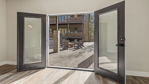 Een open deur die leidt naar een terras met een metselwerk vloer en een balkon.
