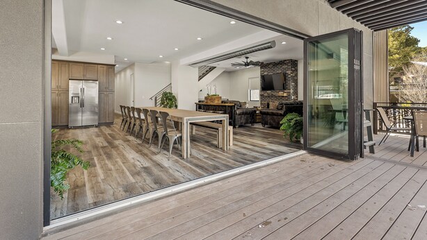 Een moderne keuken met roestvrijstalen apparatuur, een eethoek met houten meubels, en een terras met buitenmeubilair.