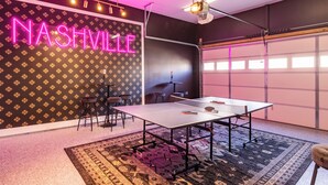 Huoneessa on pingispöytä, neonvalo, jossa lukee ”NASHVILLE”, ja kuvioitu seinä.