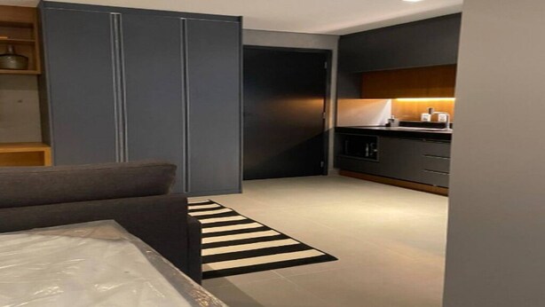A modern bedroom with a bed, a wardrobe, and a kitchen area with a countertop and cabinets. - OSCAR FREIRE 614 (Pinheiros São Paulo)