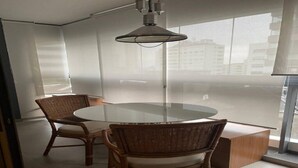 A modern dining area with a round glass table, wicker chairs, and a pendant light. - OSCAR FREIRE 614 (Pinheiros São Paulo)