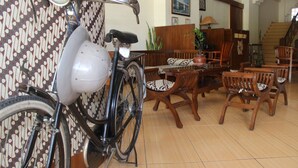 A dining area with wooden furniture, a bicycle, and a patterned wall. - Grha Somaya (Yogyakarta)