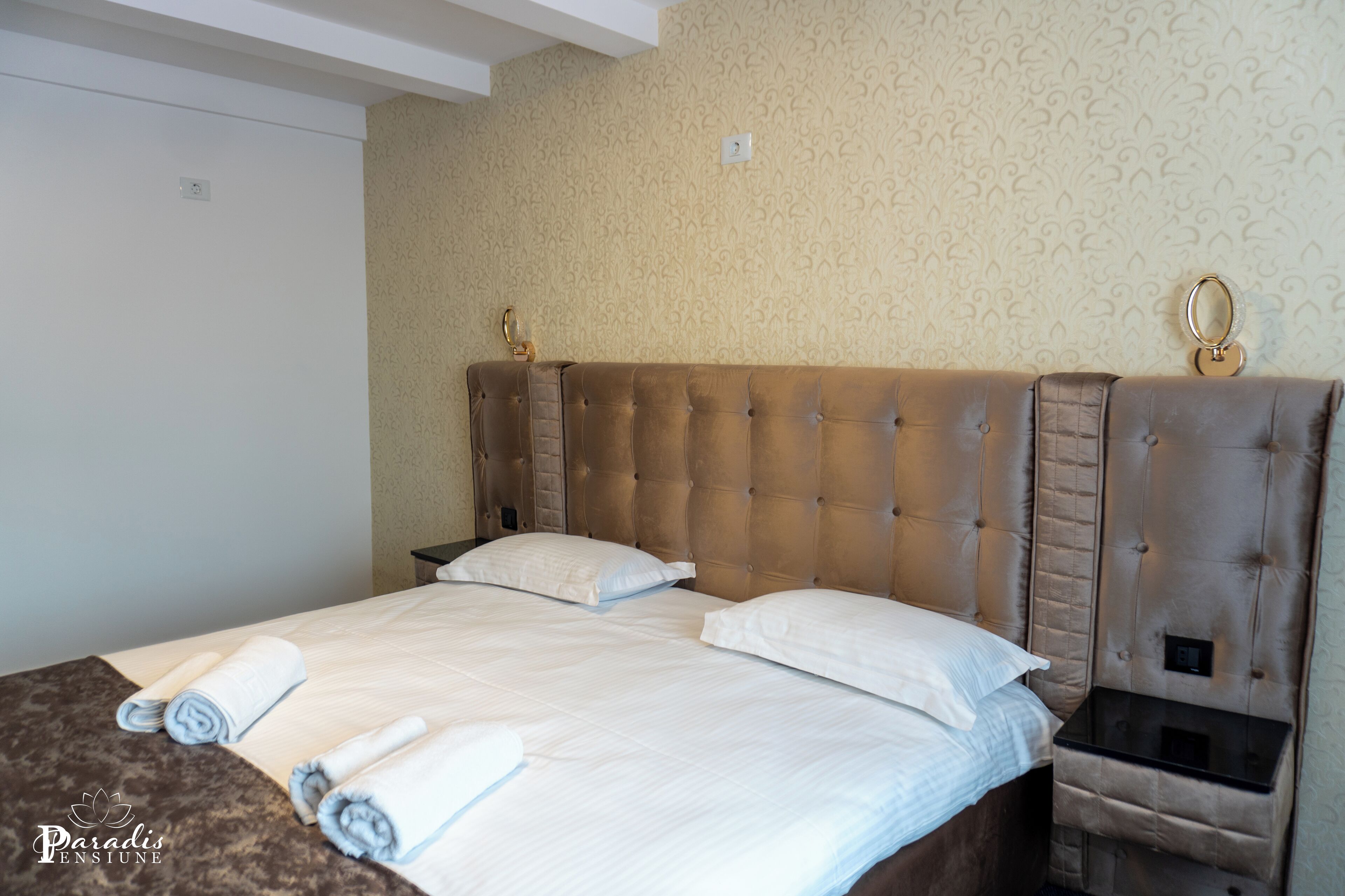 Una habitación de hotel con una cama grande, una mesita de noche y un cabecero con espejo.