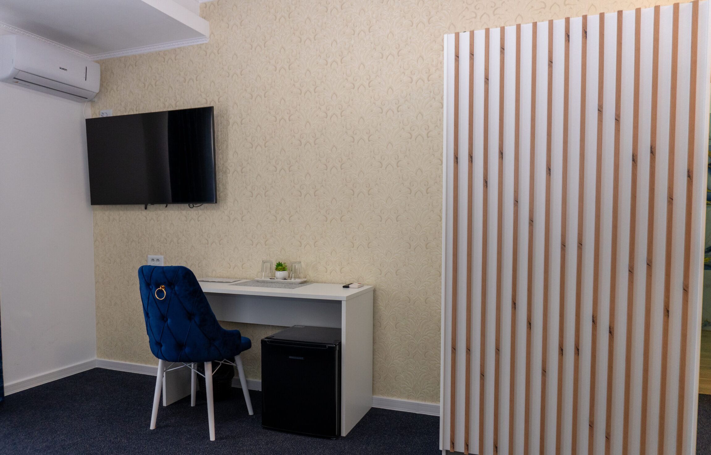 A small office space with a desk, chair, and a television on the wall.