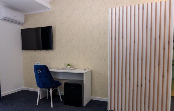Ein kleiner Büroraum mit Schreibtisch, Stuhl und Fernseher an der Wand.