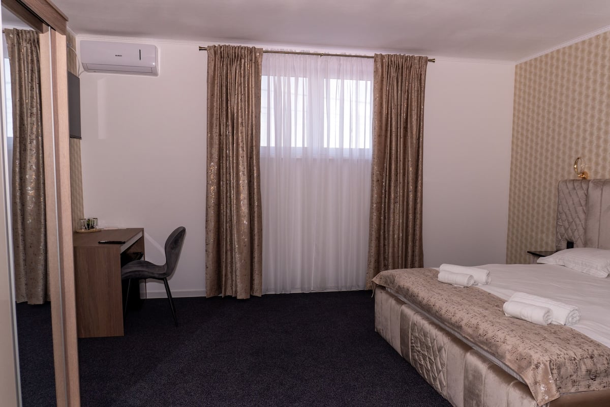 Ett hotellrum med en säng, ett skrivbord och en stol.