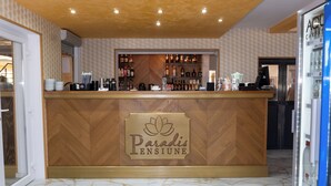 A reception area with a wooden counter, a logo, and a marble floor. - Pensiunea Paradis Buzias (Buzias)