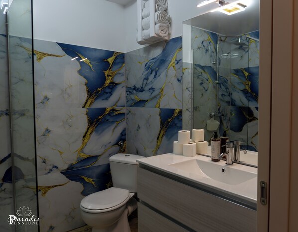 A bathroom with a toilet, sink, and mirror. The walls have a marble-like pattern. - Pensiunea Paradis Buzias (Buzias)