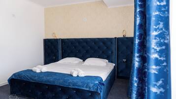 Een slaapkamer met een groot bed, hoofdeinde en gordijn.
