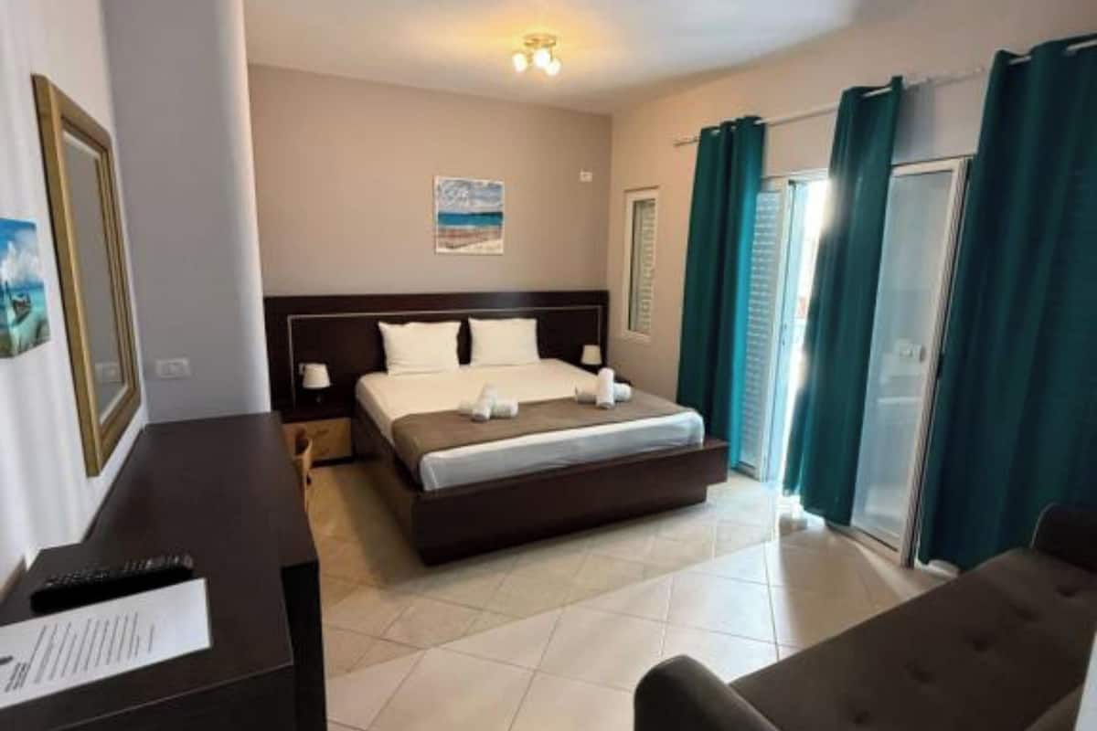A hotel room with a bed, a desk, a chair, and a view of the outside.