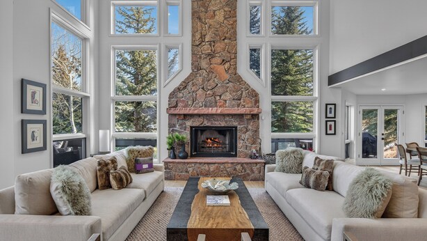 Amplia sala de estar con chimenea de piedra, ventanas grandes y dos sofás con almohadones mullidos.