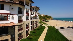 Een hotel met meerdere verdiepingen, balkons, uitzicht op het strand en een parkeerplaats.
