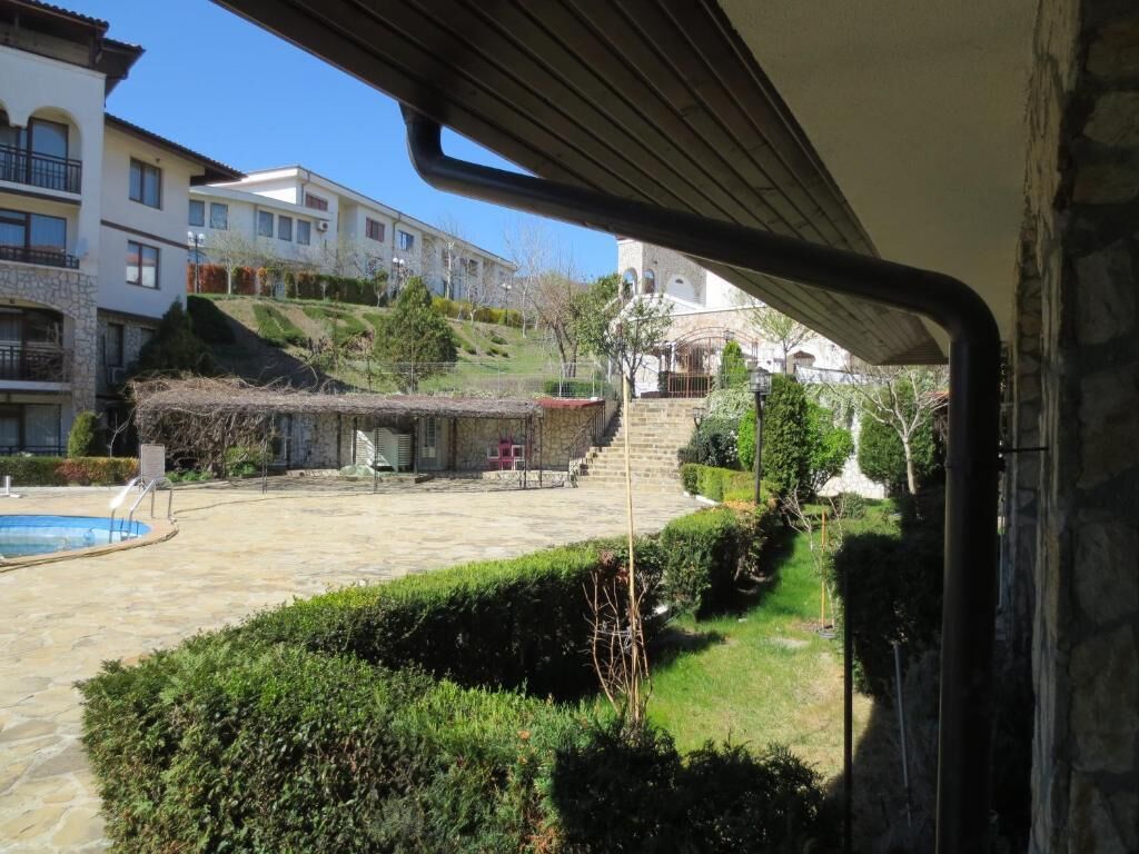 A courtyard with a swimming pool, stone flooring, and a view of multi-story buildings in the background.
