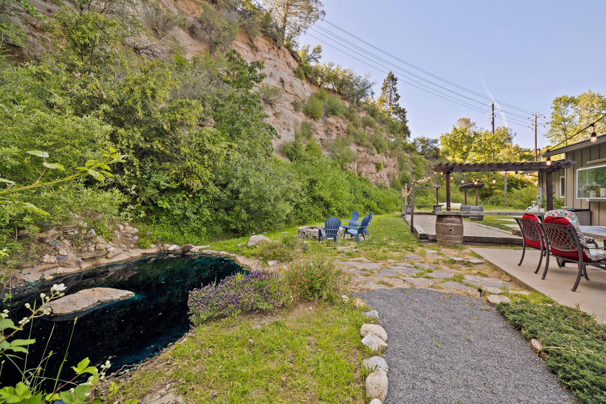 A patio area with outdoor seating, a small pond, and a view of a rocky hillside.