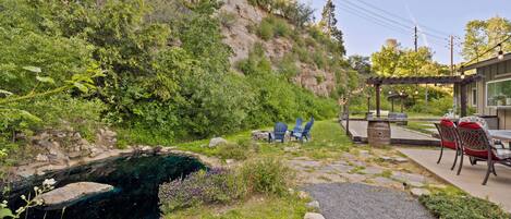 A patio area with outdoor seating, a small pond, and a view of a rocky hillside.