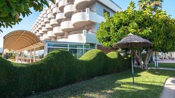 Un edificio moderno con un diseño de balcón circular único, un área exterior cubierta y jardines bien cuidados.
