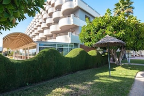 Un edificio moderno con un diseño de balcón circular único, un área exterior cubierta y jardines bien cuidados.