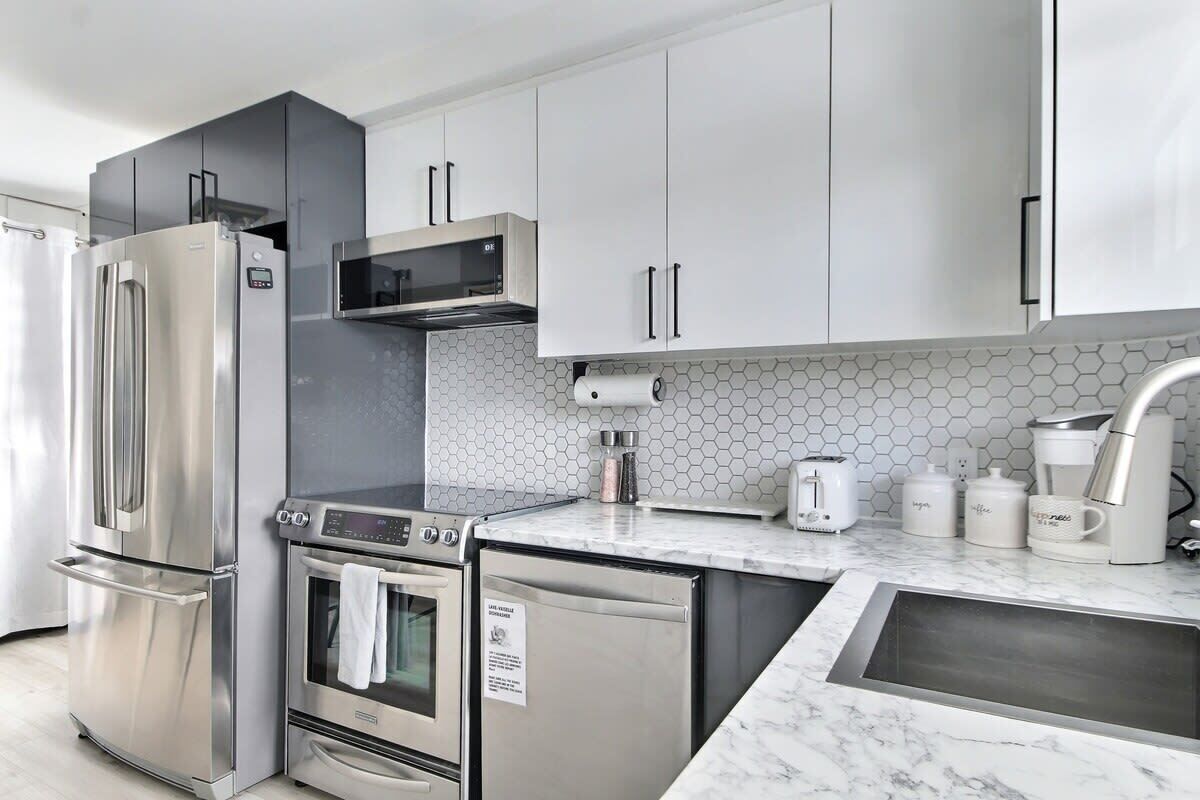 A modern kitchen with stainless steel appliances, a microwave, a toaster, and a coffee maker.
