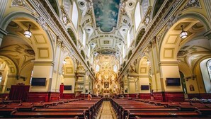 Une vue intérieure d’une église, avec des rangées de bancs et des décorations ornementales au plafond.