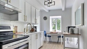 Una cocina moderna con armarios blancos, horno empotrado y comedor con mesa y sillas.