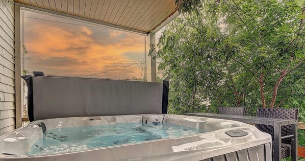 Un jacuzzi con vista a un atardecer y árboles.