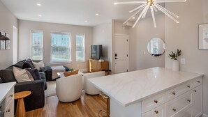 Un salon moderne avec un canapé, un pouf et un îlot central en marbre blanc.