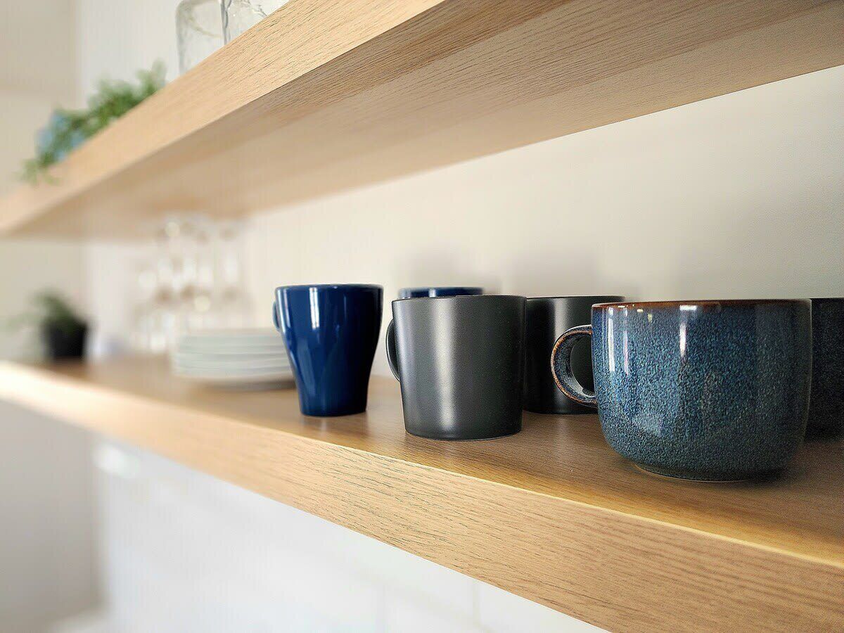Un estante de madera con tres tazas de cerámica.