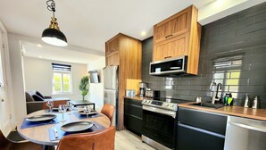 Et moderne køkken med spiseplads, med rustfrie stålens apparater, træskabe og en backsplash med sorte fliser.