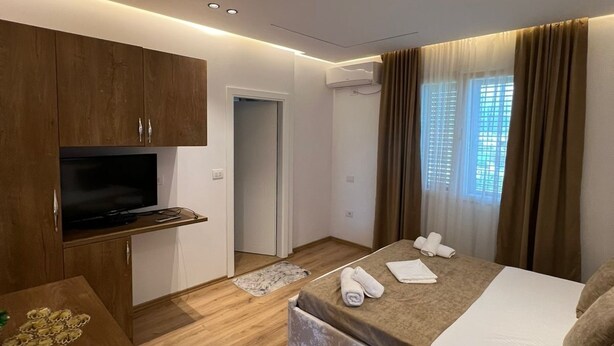 Una moderna camera d'albergo con un letto, una televisione, mobili in legno e una finestra con tende.