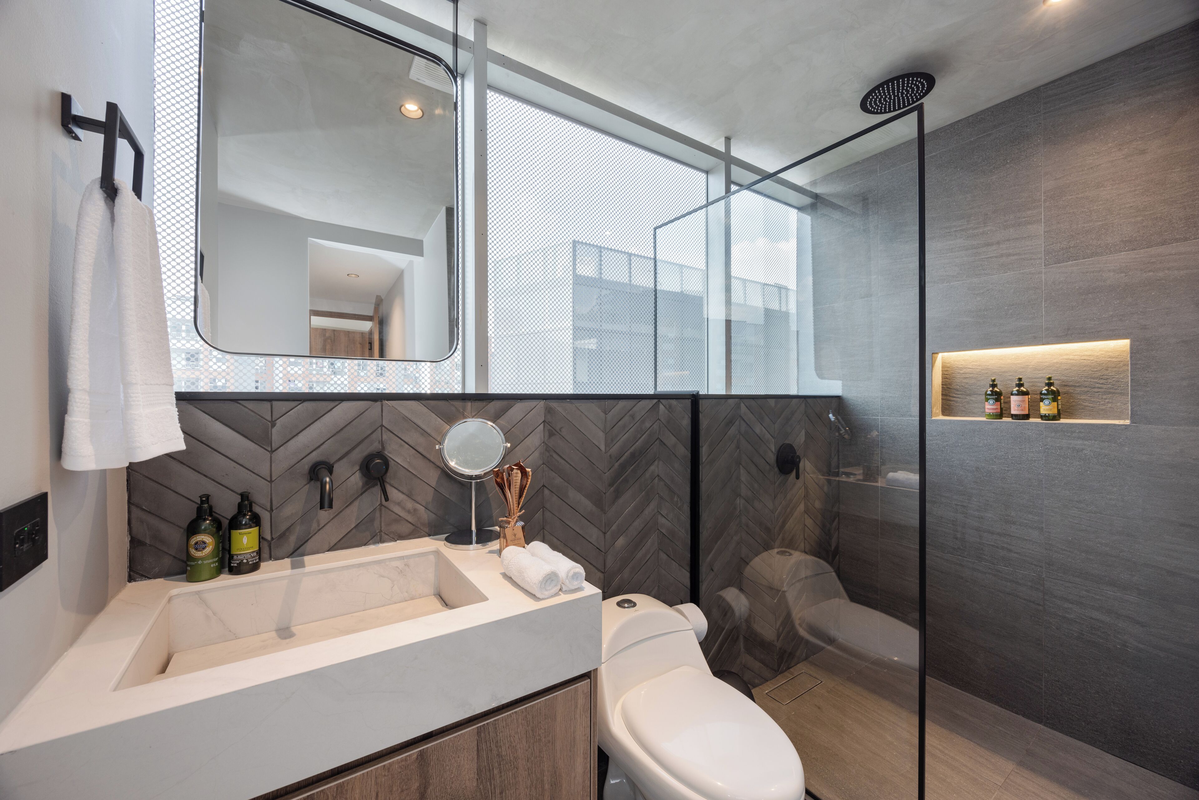 Un baño moderno con un espejo grande, un lavabo, un inodoro y una zona de ducha.