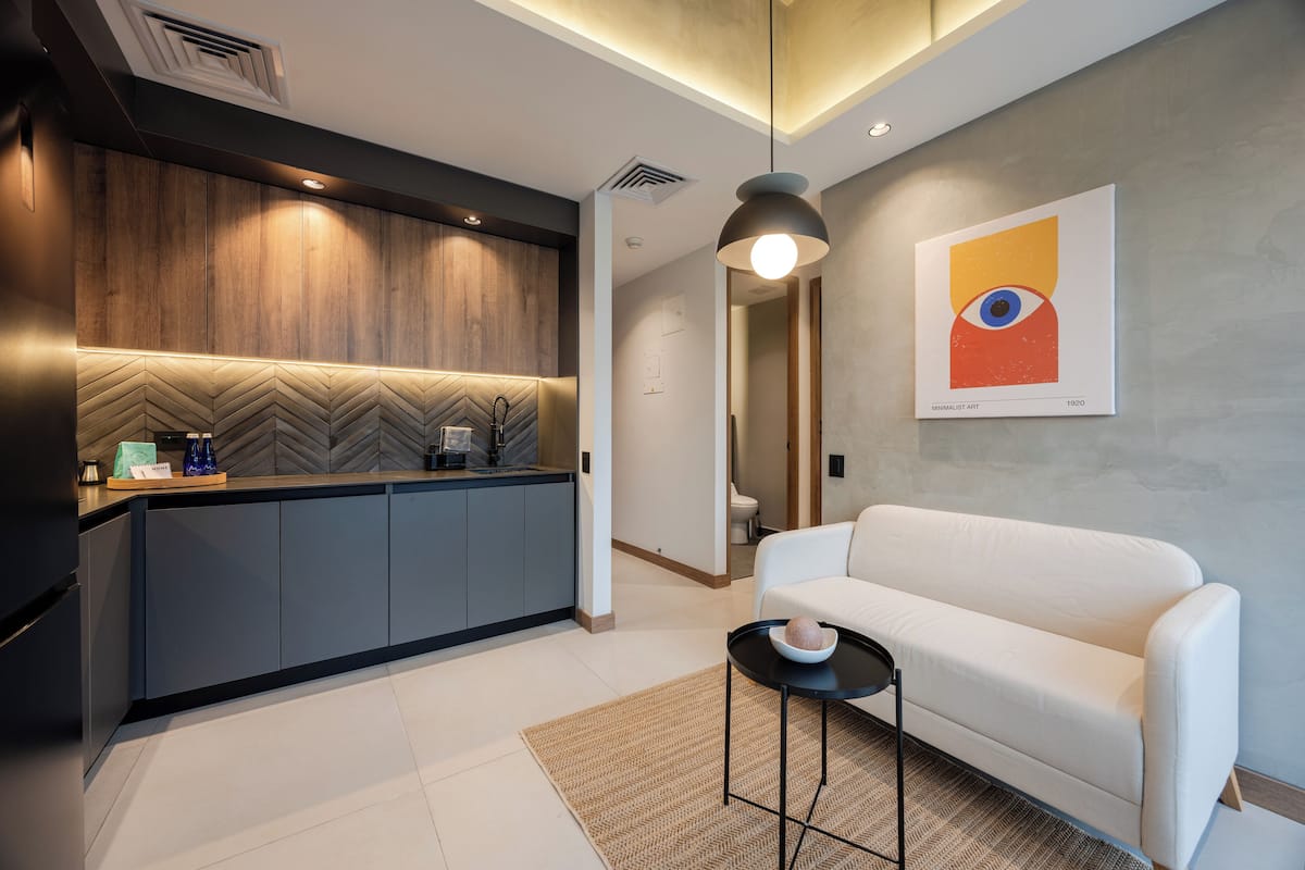 A modern kitchen with a herringbone backsplash, a white sofa, and a minimalist art piece on the wall.