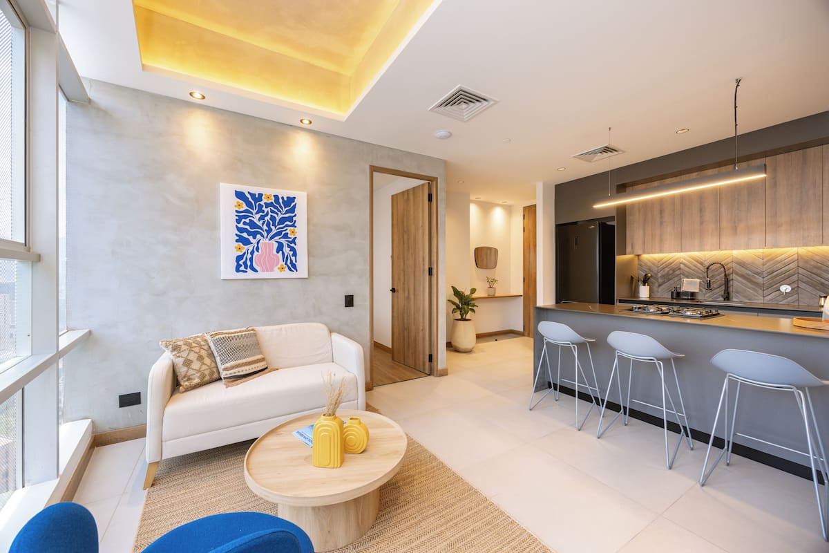 A modern living room with a sofa, coffee table, and bar stools.