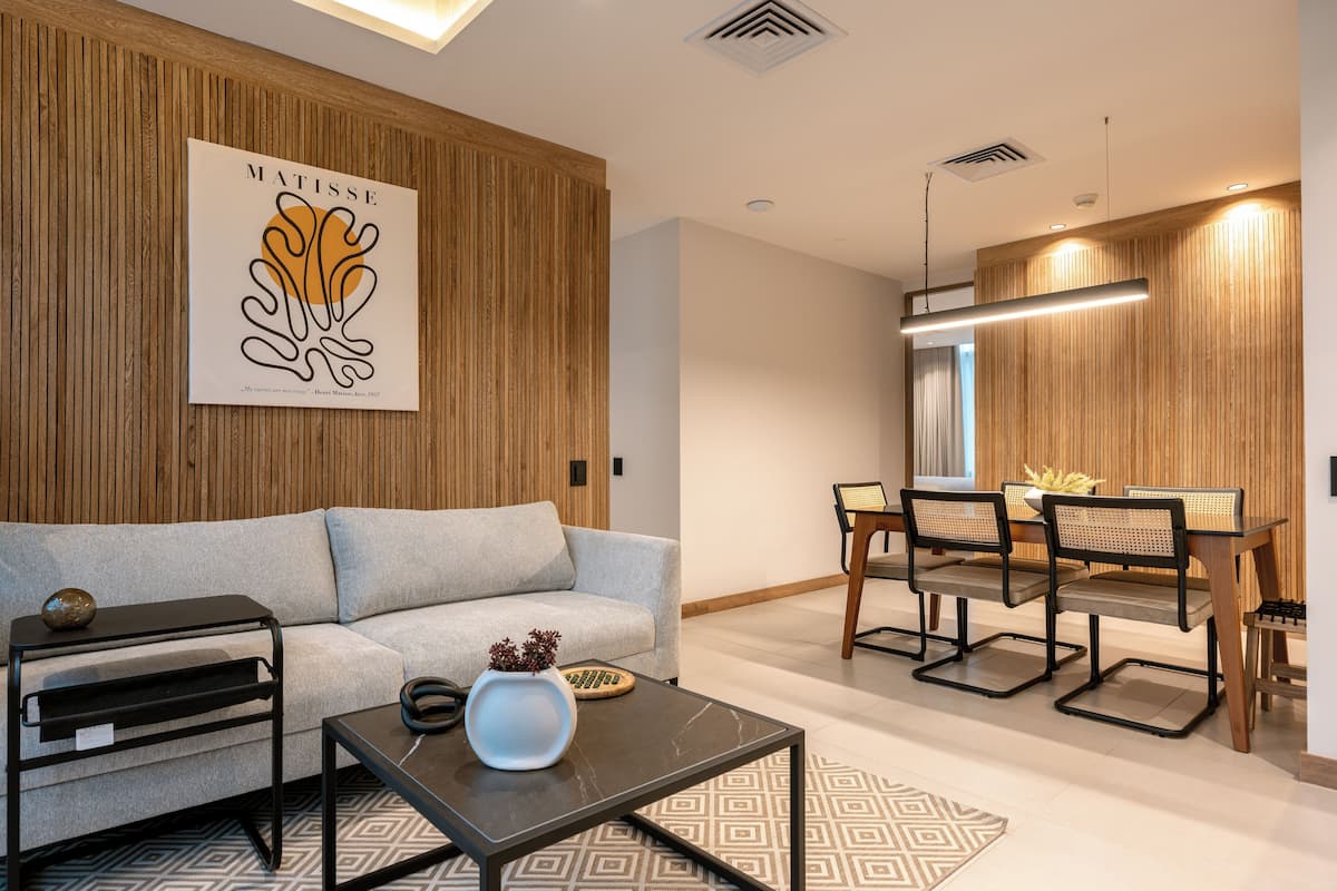 A modern living room with a sofa, coffee table, and dining area with chairs and a table.