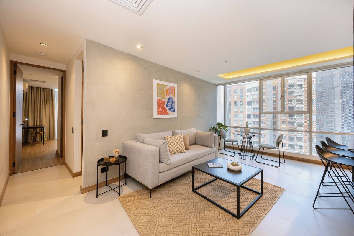 A modern living room with a sofa, coffee table, and dining area.