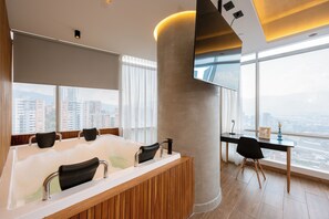 A modern bathroom with a large bathtub, a wooden vanity, and a desk with a chair. - Bio 26 Apartments  (Medellín)
