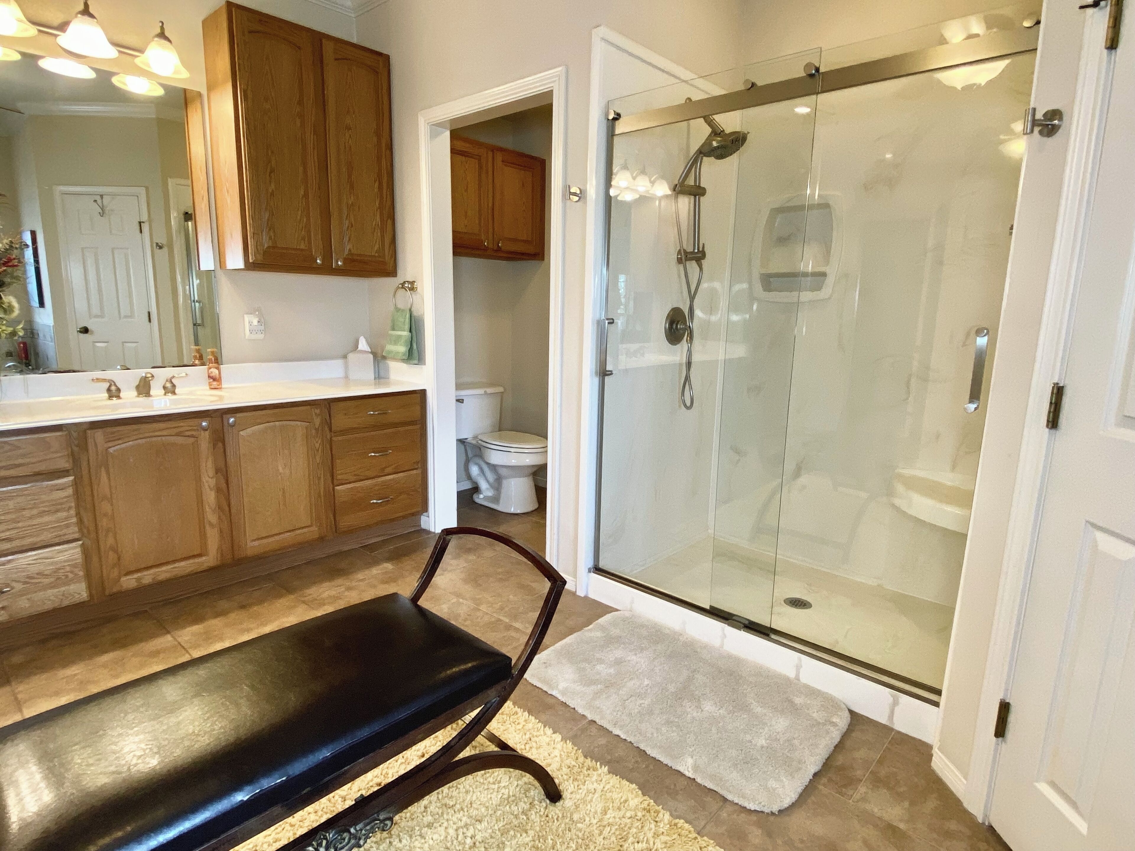 Une salle de bain moderne avec une douche à parois de verre, des meubles en bois et un banc.