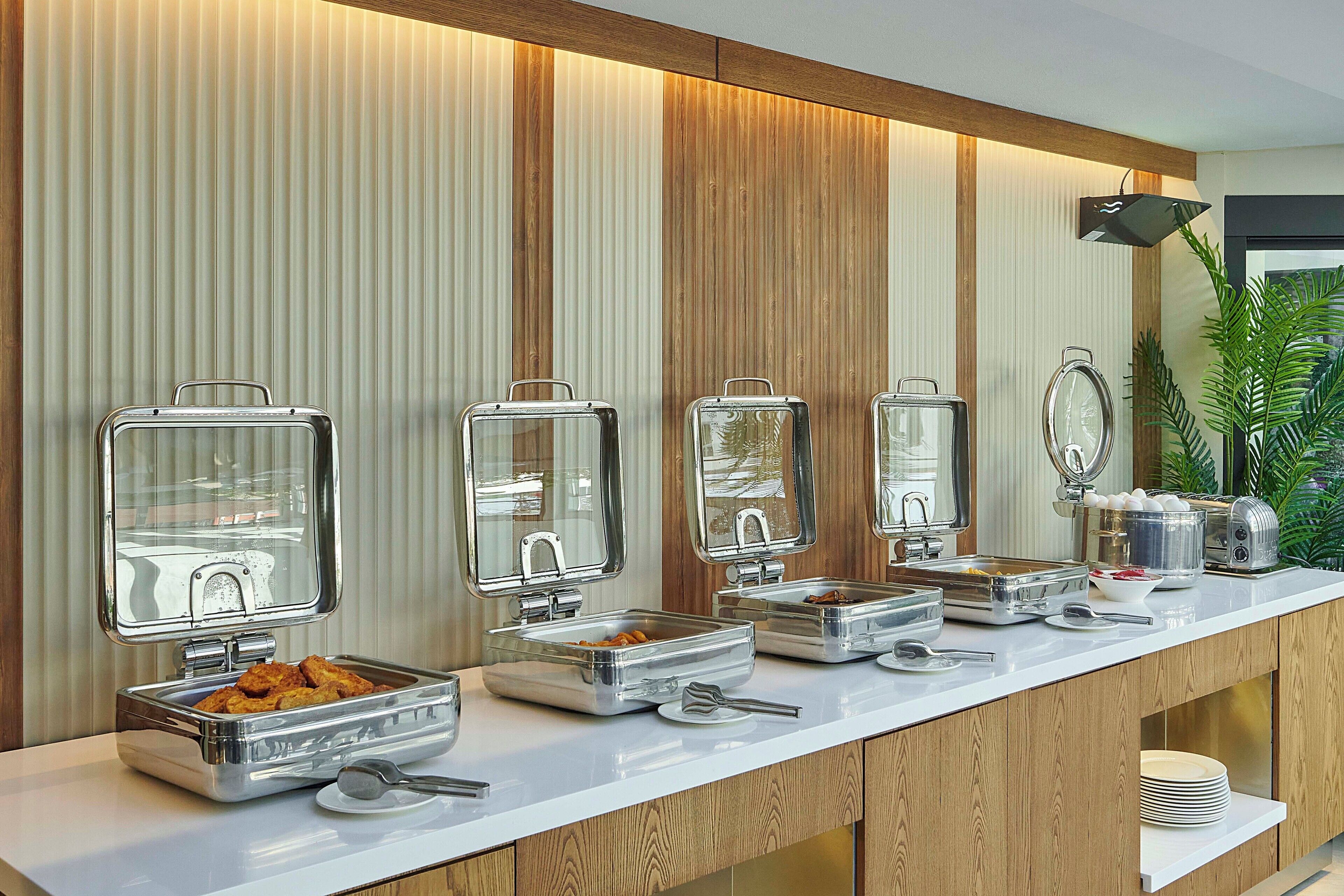 A buffet setup with multiple serving stations, including trays of food and utensils.