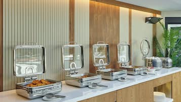 Un buffet avec plusieurs points de service, comprenant des plateaux de nourriture et des ustensiles.